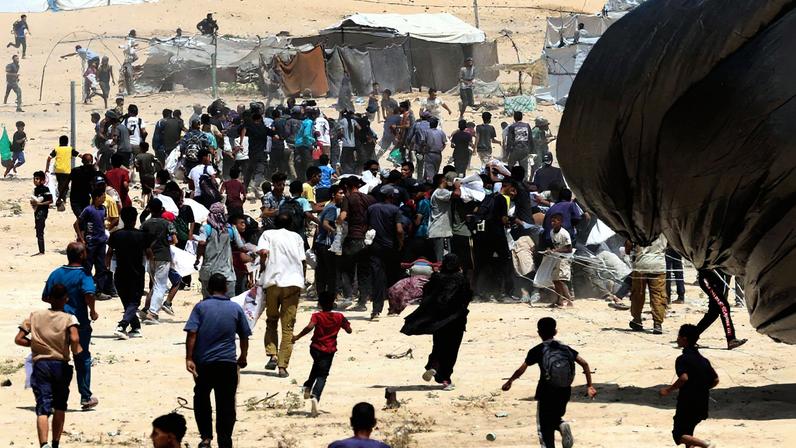 Palestinos correm em direção aos pacotes de ajuda lançados de avião em Deir Al-Balah, no centro da Faixa de Gaza (Foto: Ramadan Abed/Reuters)