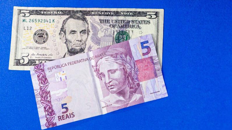 Notas de cinco dólares e cinco reais; na terça, o dólar fechou em firme queda de 1,02%, cotado a R$ 5,387, e a Bolsa disparou 1,66%, a 137.878 pontos (Foto: Pedro Affonso/Folhapress)