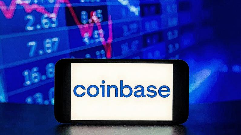 O logotipo da Coinbase é exibido na tela de um telefone celular com porcentagens do mercado de ações ao fundo. (Foto: Idrees Abbas | Sopa Images | Lightrocket | Getty Images)