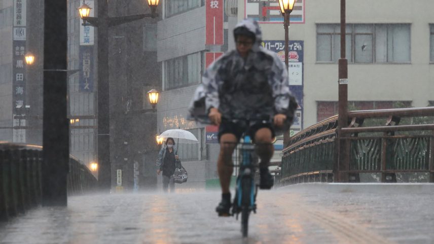 Chuvas no Japão: pessoas caminham e pedalam sob forte chuva na cidade de Kumamoto, no sudoeste do país, em 11 de agosto de 2025. (Foto: STR/JIJI Press/AFP/Getty Images)