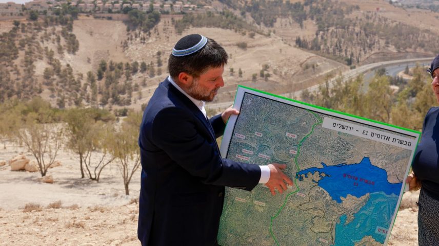 O ministro das Finanças de Israel, Bezalel Smotrich, segura um mapa de uma área perto do assentamento de Maale Adumim, um corredor terrestre conhecido como E1, na Cisjordânia. 14/08/2025. (Foto: Menahem Kahana/AFP)