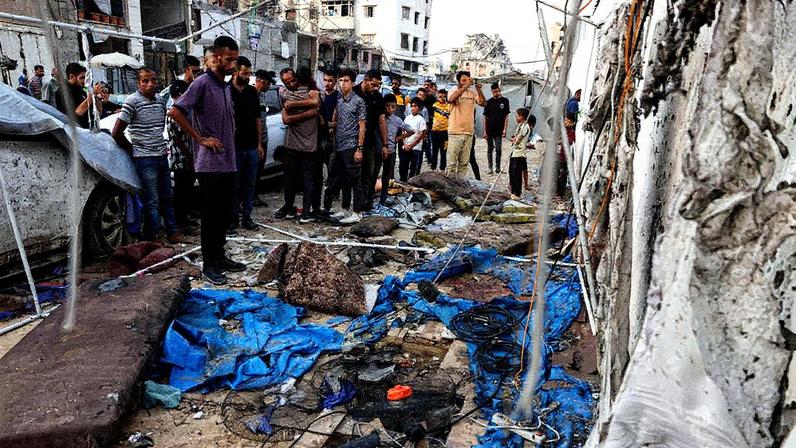 Pessoas observam os destroços no local onde estava a barraca usada por jornalistas da rede al-Jazeera na Cidade de Gaza, atingida por um drone de Israel (Foto: BASHAR TALEB / AFP)