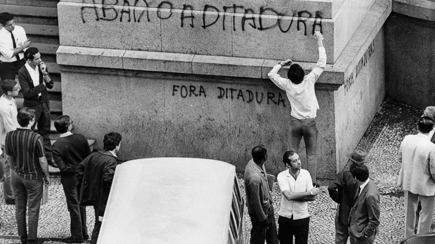 Estudante pichando fachada de prédio com os dizeres "Abaixo a Ditadura". (Foto: AGENCIA JB/Dedoc)