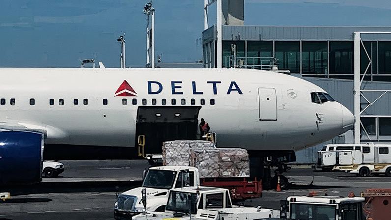 Um trabalhador descarrega pacotes de um avião no aeroporto JFK de Nova York. (Foto: Reprodução)