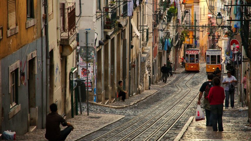 Pedestres e bondinhos circulam em uma rua de Lisboa (Foto: Unsplash/Divulgação)