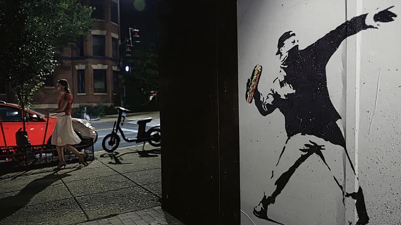 Uma pessoa passa por uma obra de arte que retrata o ex-funcionário do DOJ, Sean Charles Dunn, exibida contra a parede de um restaurante em 17 de agosto de 2025, no bairro de Adams Morgan, em Washington. (Foto: Tom Brenner | The Washington Post | Getty Images)
