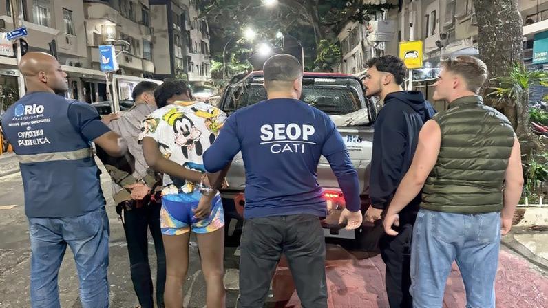 Agentes da Seop com os dois suspeitos presos e algemados (Foto: Seop/Divulgação)