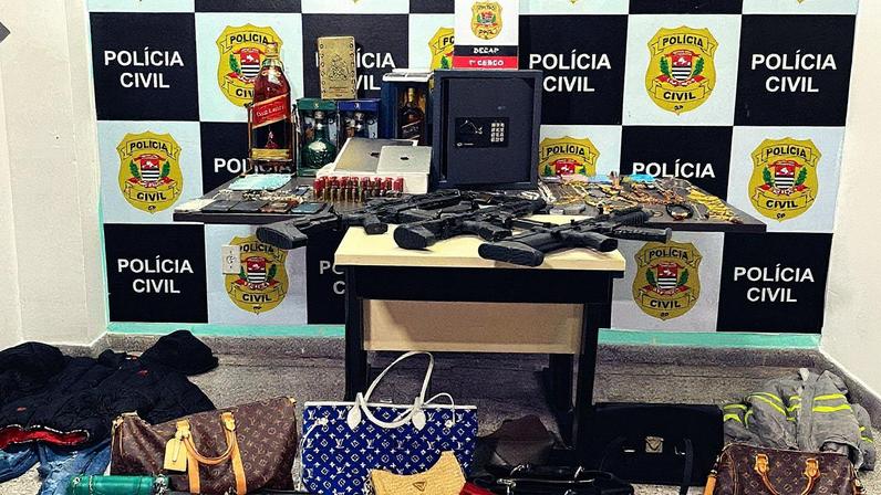 Armas, bebidas, bolsas de grife, joias e aparelhos eletrônicos apreendidos em operação contra quadrilha especializada em roubo a condomínios (Foto: Lucas Lacerda/Folhapress)