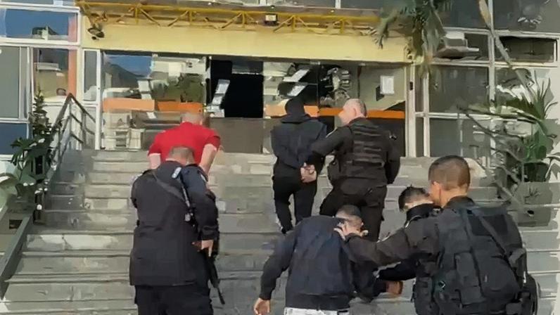 Grupo ao chegar na delegacia sendo conduzido pelos PMs (Foto: Reprodução)