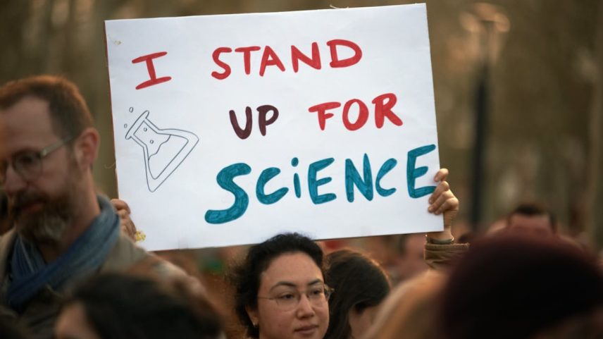 Uma mulher segura um cartaz de papelão que diz “Defendo a ciência”. (Foto: Alain Pitton/Getty Images)