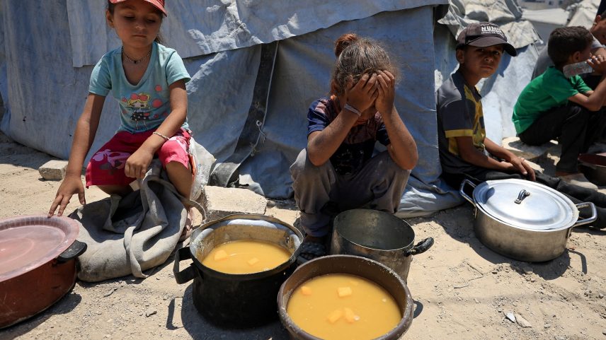 Crianças palestinas reagem perto de panelas de comida de uma cozinha de caridade, em meio a uma crise de fome, na Cidade de Gaza, 25 de julho de 2025. (Foto: REUTERS/Dawoud Abu Alkas)