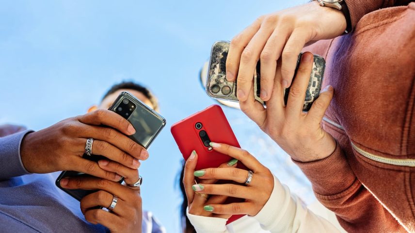 Três jovens usando o celular. Provavelmente, não para contar suas vidas nas redes sociais. (Foto: Xavier Lorenzo/Getty Images)