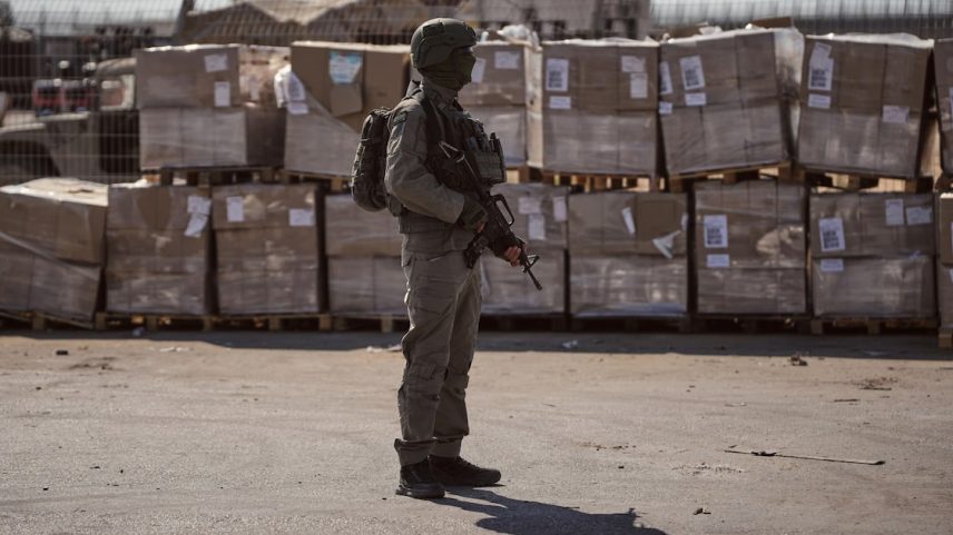 Imagem de 24 de julho mostra um soldado israelense vigiando pacotes de ajuda humanitária na fronteira de Israel com a Faixa de Gaza. Militares israelenses gravaram milhões de chamadas de palestinos comuns após parceria com a Microsoft (Foto: Ohad Zwigenberg/AP)