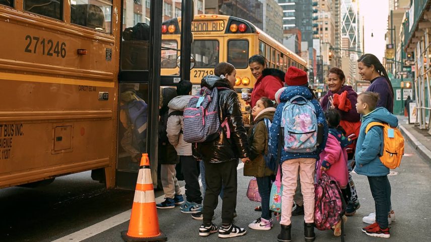 Crianças migrantes aguardam um ônibus em Nova York, em dezembro de 2023. (Foto: Andres Kudacki/AP)