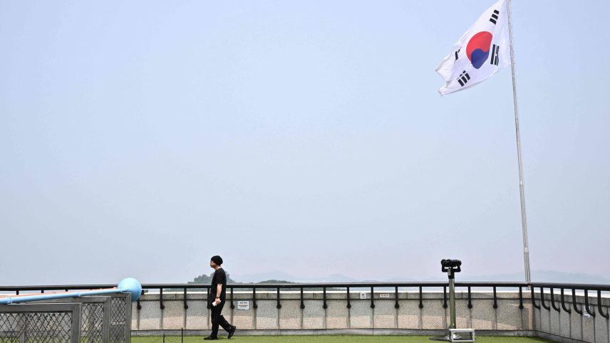 Homem caminha sob a bandeira da Coreia do Sul em um mirante de onde os visitantes podem olhar para a Coreia do Norte (Foto: Anthony Wallace - 11.jun.24/AFP)