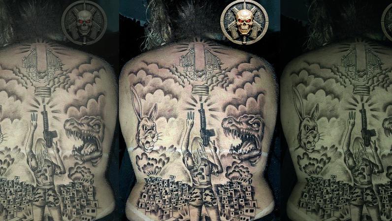Tatuagem nas costas de Eweline Passos Rodrigues, a Diaba Loira: uma mulher segura um fuzil, ao lado de um coelho e de um jacaré, em referência a uma grife (Foto: Reprodução)