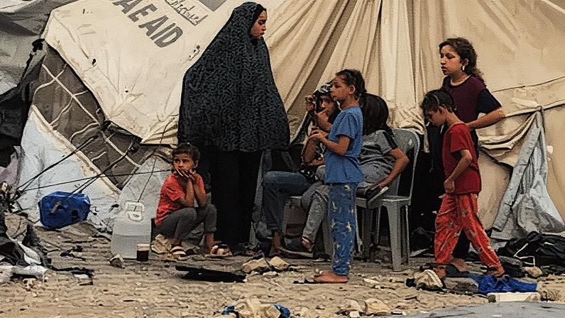 Uma família está na porta de uma loja de campanha em Gaza (Foto: Reprodução)