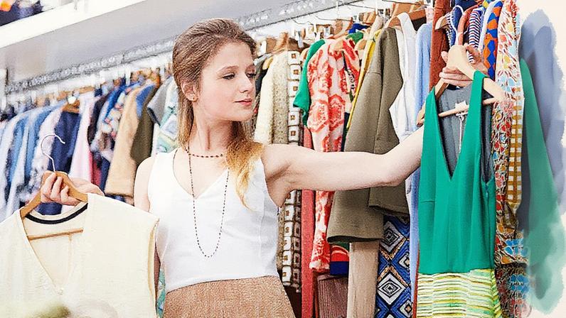 Consumidora indecisa entre dois vestidos em uma loja de roupas (Foto: Reprodução)