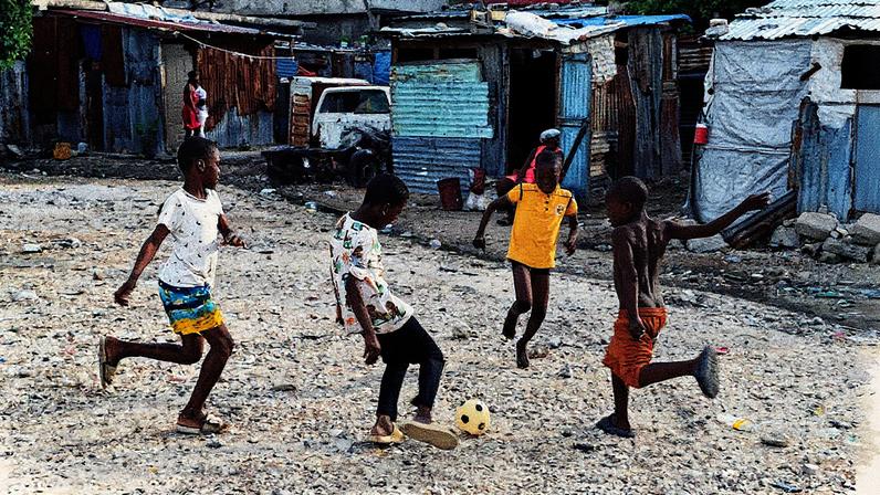 Crianças brincam em uma rua de Puerto Príncipe, Haiti, em um dia ensolarado (Foto: Reprodução)