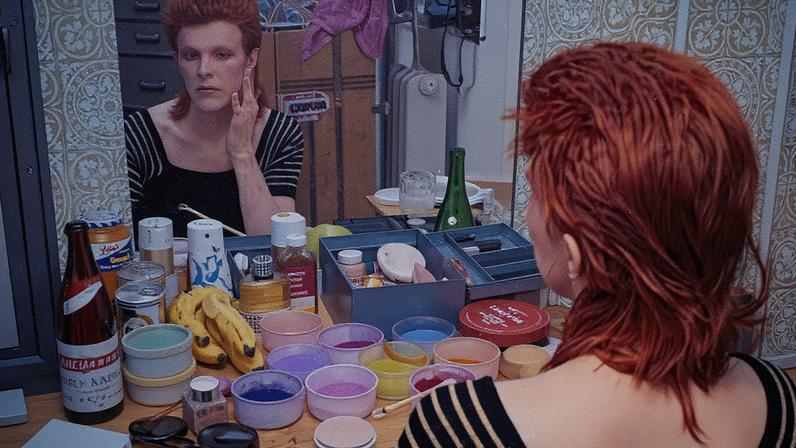 David Bowie aplica maquiagem como seu alter ego Ziggy Stardust em uma fotografia de 1973 (Foto: Reprodução)