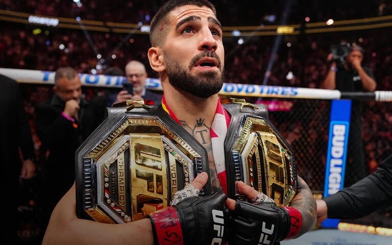 Ilia Topuria segura dois cinturões após a vitória contra Charles Oliveira na luta principal do UFC 317. (Foto por Jeff Bottari/Zuffa LLC)