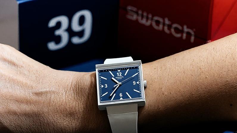 Modelo da relojoaria suíça Swatch chamado "WHAT IF...TARIFFS?" com os números 3 e 9 invertidos em seu mostrador, representando os 39% de tarifas de importação impostas pelo presidente dos EUA, Donald Trump, no mês anterior, é exibido no pulso em uma loja Swatch em Genebra, Suíça (Foto: Reprodução)