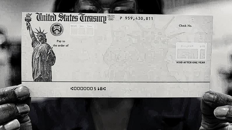 Funcionário segura um cheque em branco do Tesouro dos EUA antes de ser impresso na instalação de impressão do Tesouro em Filadélfia (Foto: Reprodução)