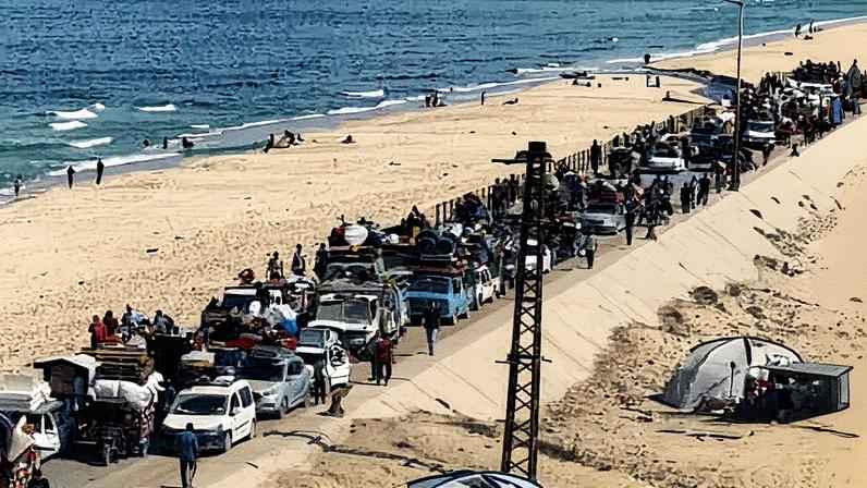 A long queue of cars, with suitcases and other possessions strapped to them, stretches down a coastal road. They do not appear to be moving. Photograph: Mahmoud Issa/Reuters