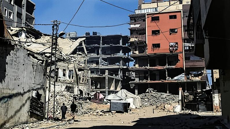 Several people walk through a scene of destruction after an Israeli airstrike. Destroyed buildings, piles of rubble and tents are in the street, seen in a frame of black shadow with a clear blue sky in the background Photograph: Mohammed Saber/EPA