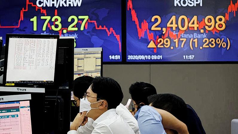 Negociante de câmbio usa máscara enquanto trabalha em frente a painéis eletrônicos que mostram o índice KOSPI em um banco em Seul, Coreia do Sul (Foto: Reprodução)