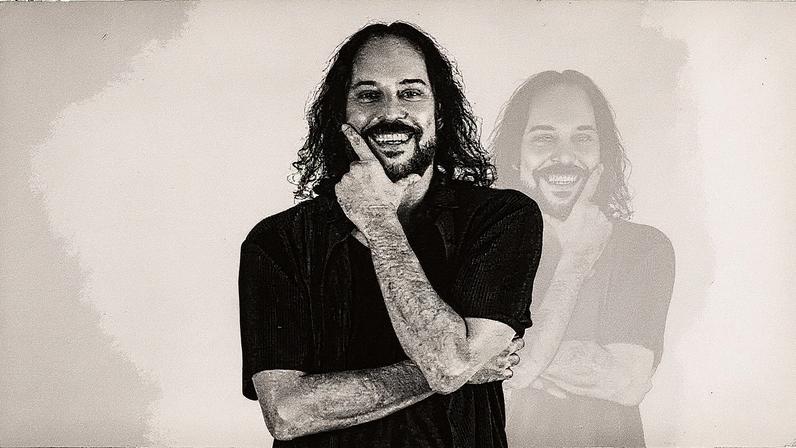 Homem com cabelo curto e barba usa camiseta e boné, posando para a foto em um ambiente interno (Foto: Reprodução)