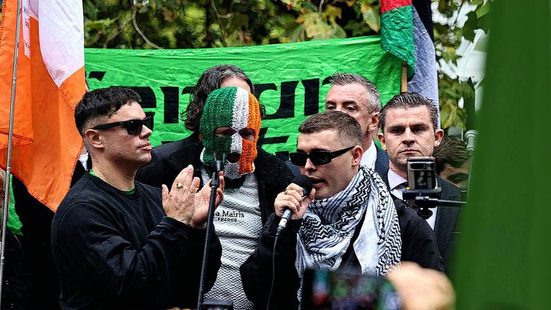 Kneecap's Mo Chara (right, with microphone) addressing supporters with his bandmates, DJ Próvaí and Móglaí Bap, following the dismissal of his terror case on Sept. 26. Neil P. Mockford/Getty Images