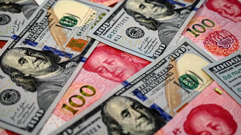 Notas de 100 yuans e notas de 100 dólares americanos dispostas lado a lado (Foto: Reprodução)