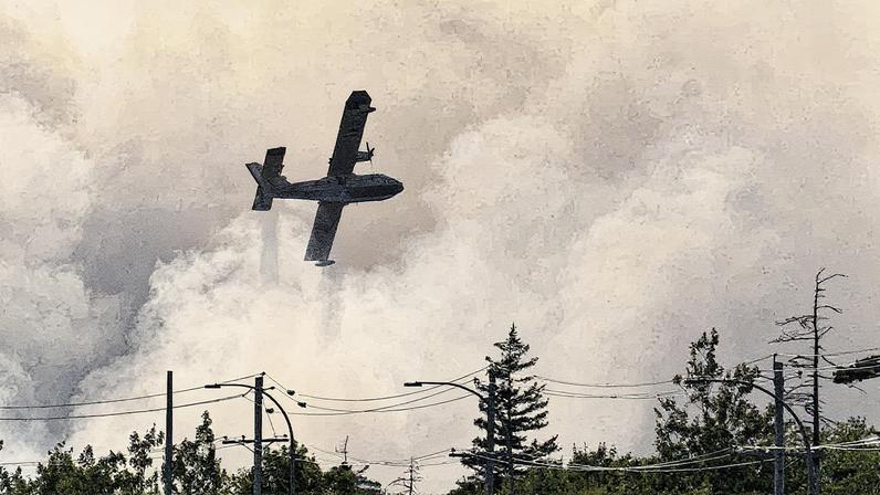 Avião tenta apagar incêndio florestal em Bayers Lake, Nova Escócia, enquanto evacuam a área (Foto: Reprodução)