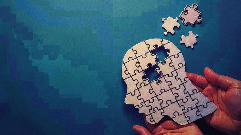 Homem de terno fala ao microfone durante apresentação em um palco com gráfico ao fundo (Foto: Reprodução)