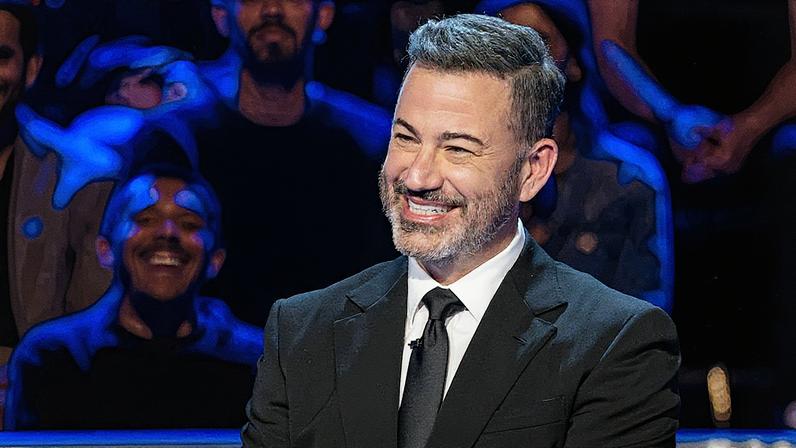 Homem em pé em um palco, falando ao microfone, com uma tela grande ao fundo exibindo um gráfico azul com tendência de alta (Foto: Reprodução)