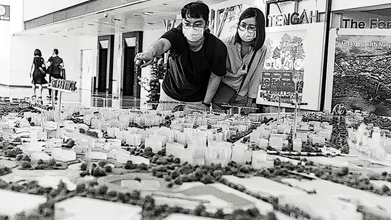 Getty Images A man and woman in medical masks lean over a city model showing lots if trees among the white buildings (Credit: Getty Images)