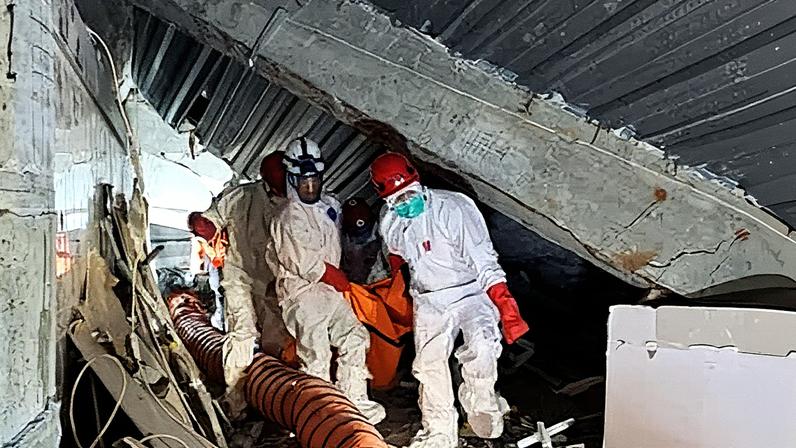 Indonesian rescuers carry a body through the rubble of the collapsed school in Sidoarjo. The death toll from the collapse rose to 14 on Friday.