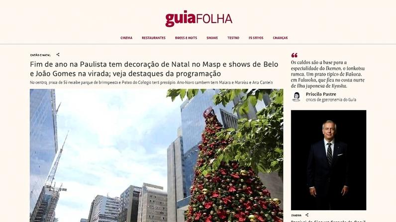 Árvore de Natal alta decorada com bolas vermelhas e douradas na Avenida Paulista, cercada por arranha-céus sob céu azul com poucas nuvens.