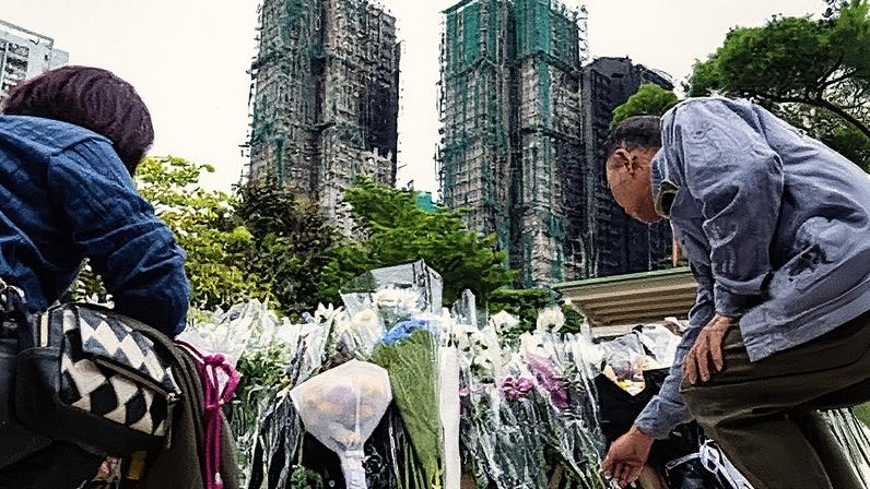 People lay flowers for the victims near the site of Wednesday’s fire at Wang Fuk Court in Hong Kong.