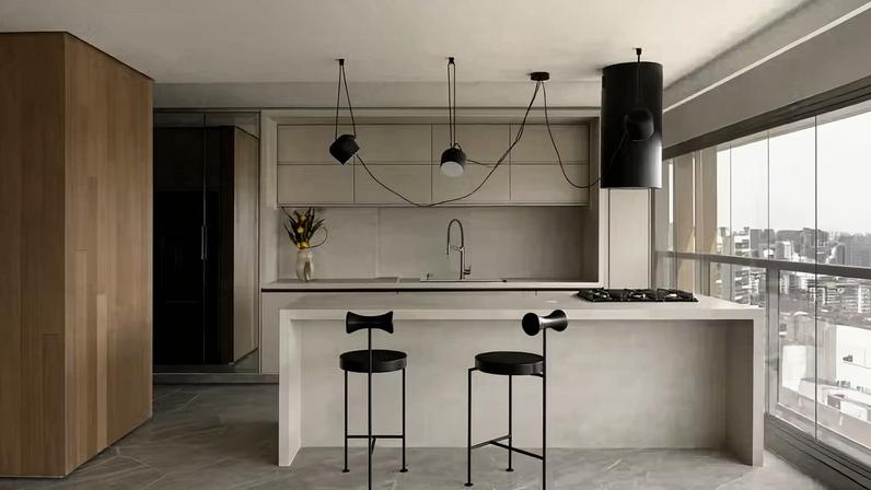 A marcenaria em laca off-white, executada pela Dell Anno Atelier, se integra à pedra Coverlam Crema Marfil da ilha, instalada pela marmoraria Mundo das Pedras, criando uma cozinha minimalista