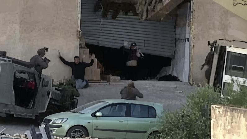 The video appears to show, at first, Israeli forces surrounding a storage facility and two men emerging to give themselves up.