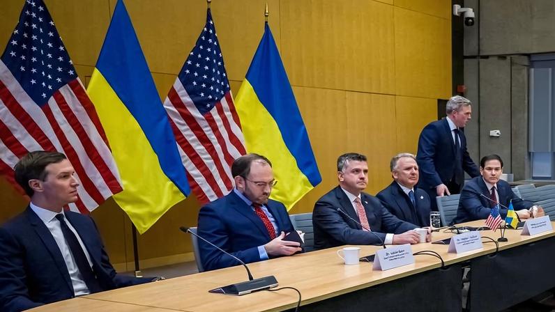 Several Trump administration officials are seen sitting at a long table in front of the national flags of the United States and Ukraine.