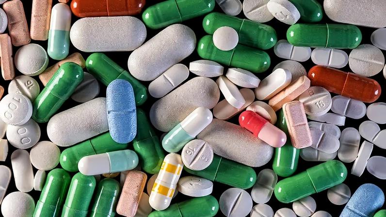 Fotografia de diferentes tipos de medicamentos em forma de comprimido e cápsula.