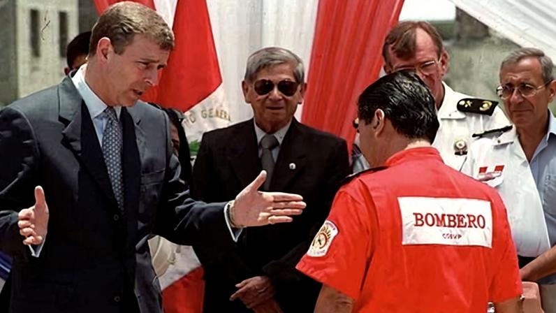 The then Prince Andrew, left, speaks with a Peruvian firefighter on 8 March 2002, during his official visit to Peru.