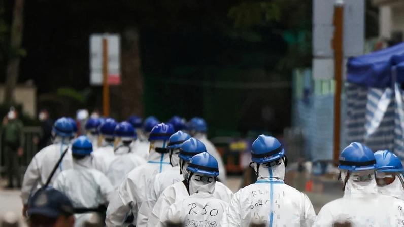 Police officers wearing PPE walk next to the Wang Fuk Court housing complex after the deadly fire in Tai Po, Hong Kong, on 3 December.