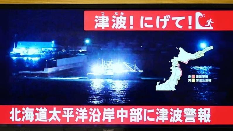 A tsunami warning is issued as live footage of a boat leaving a port is shown on a television in Sapporo, in Japan's northern Hokkaido prefecture. Photograph: Greg Baker/AFP/Getty Images