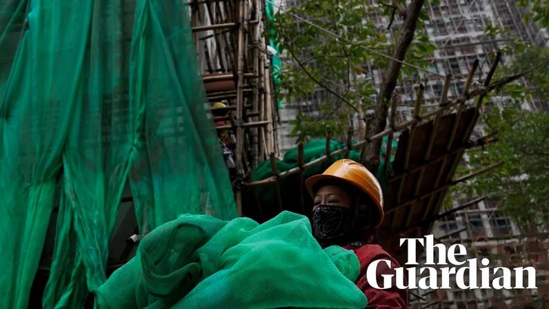 Worker removes scaffolding mesh from a building in Hong Kong.
