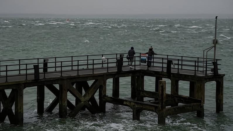 People walk along Victoria Pier in Portsmouth. Amber weather warnings were in place for areas of south Wales and south-west England on Tuesday morning.