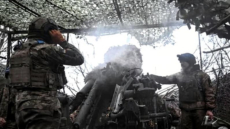 Ukrainian troops fire a howitzer towards Russian troops.